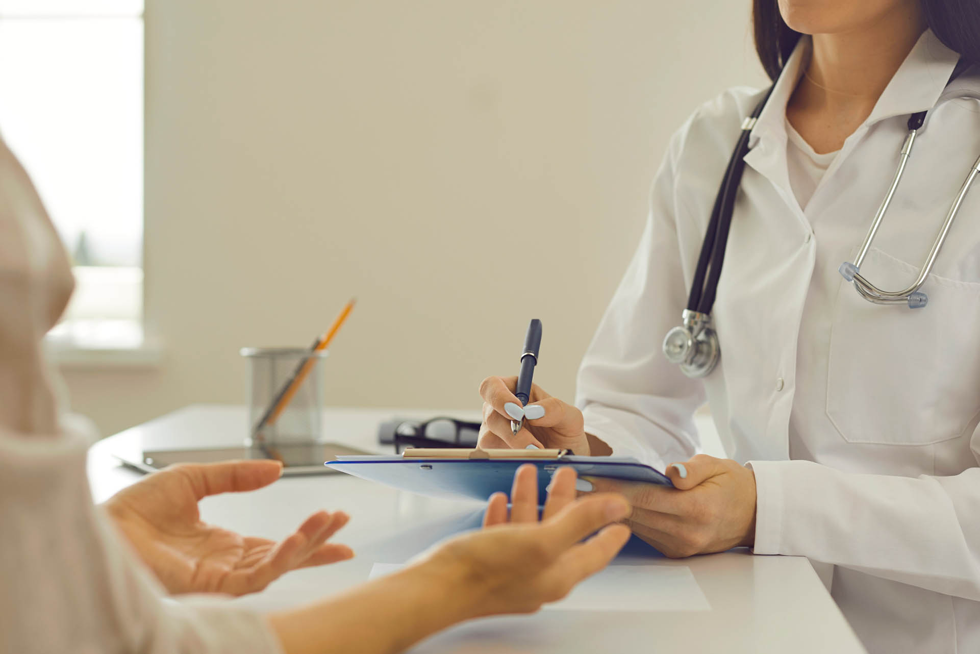 Cropped image of female doctor with clipboard listening to client's health complaints and concerns and noting down symptoms. Therapeutist keeping patient's chart writing down her personal information